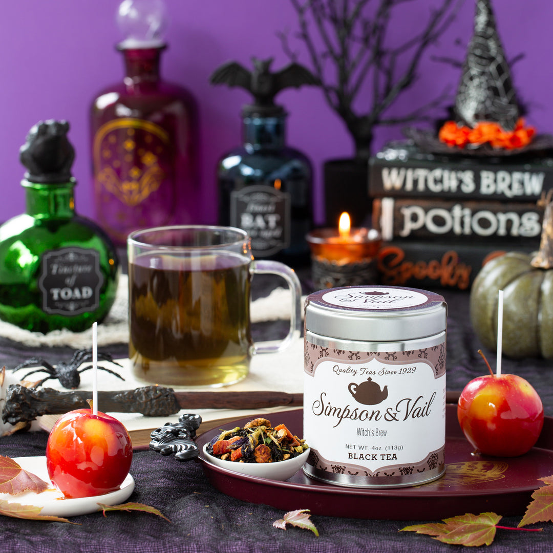Halloween-themed setup with a mug of tea, candy apples, and a canister labeled &