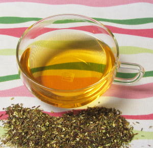 Organic Green Rooibos Herbal Tea Pile and Brewed Cup